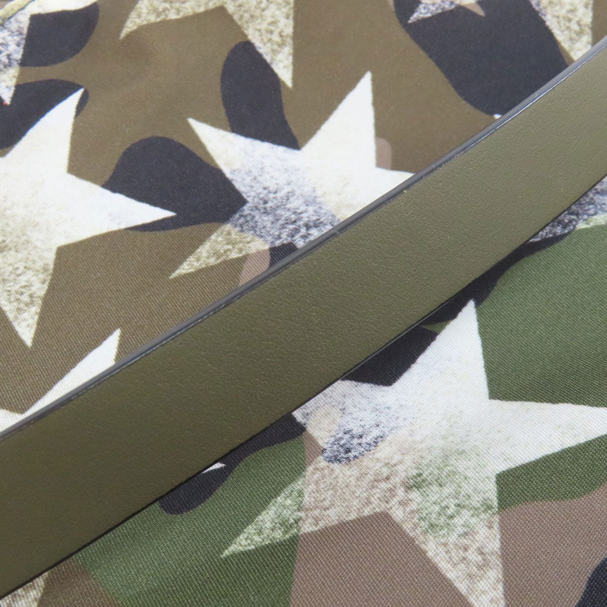 Close-up of a camouflage-patterned fabric with a green stripe.