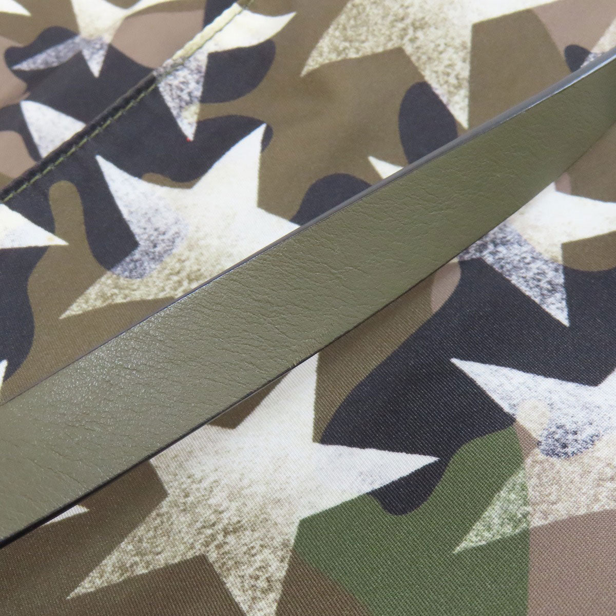 Close-up of a camouflage-patterned fabric with a green stripe