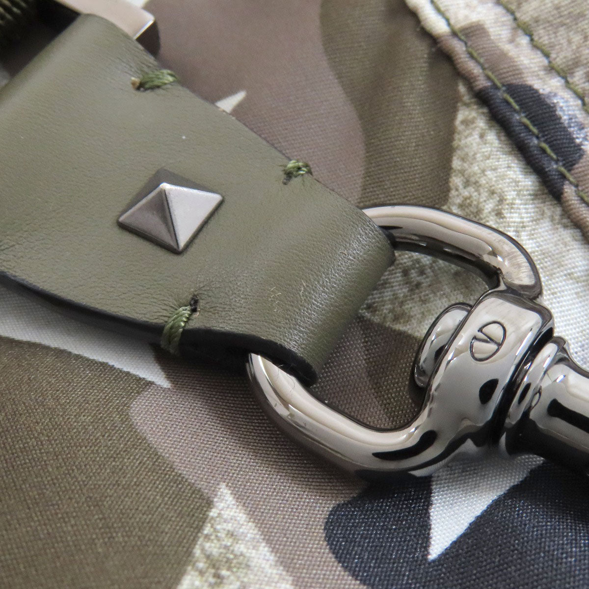 Green leather key fob with metallic keychain on camouflage fabric