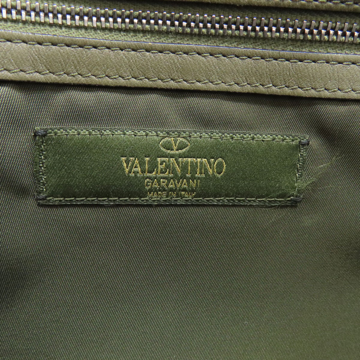 Valentino Garavani label on a green fabric surface