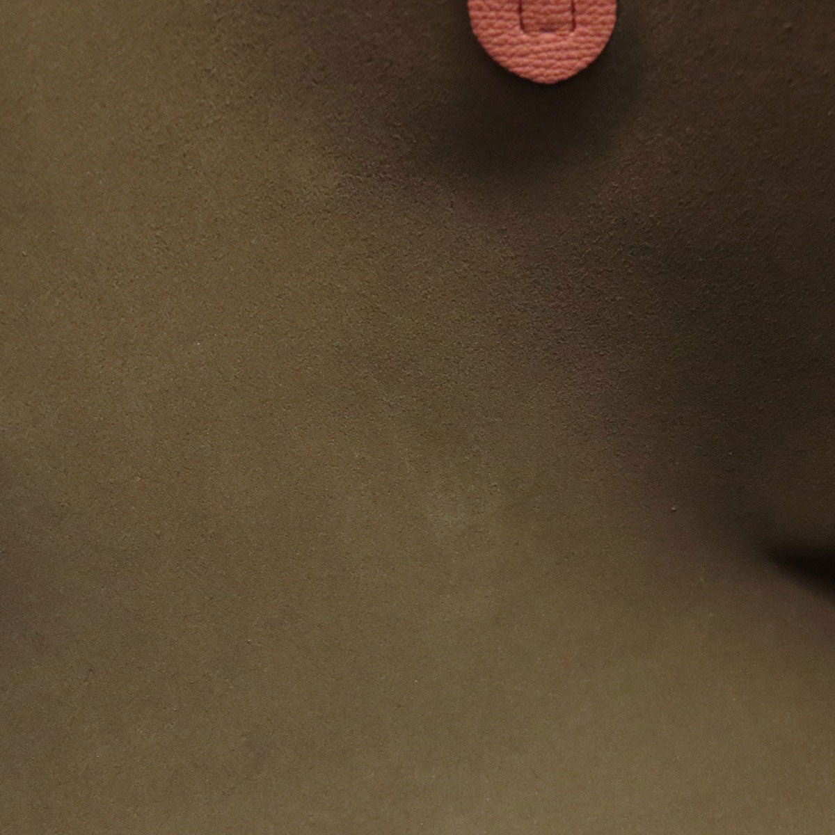 Close-up of brown fabric with a pink button on a dark background