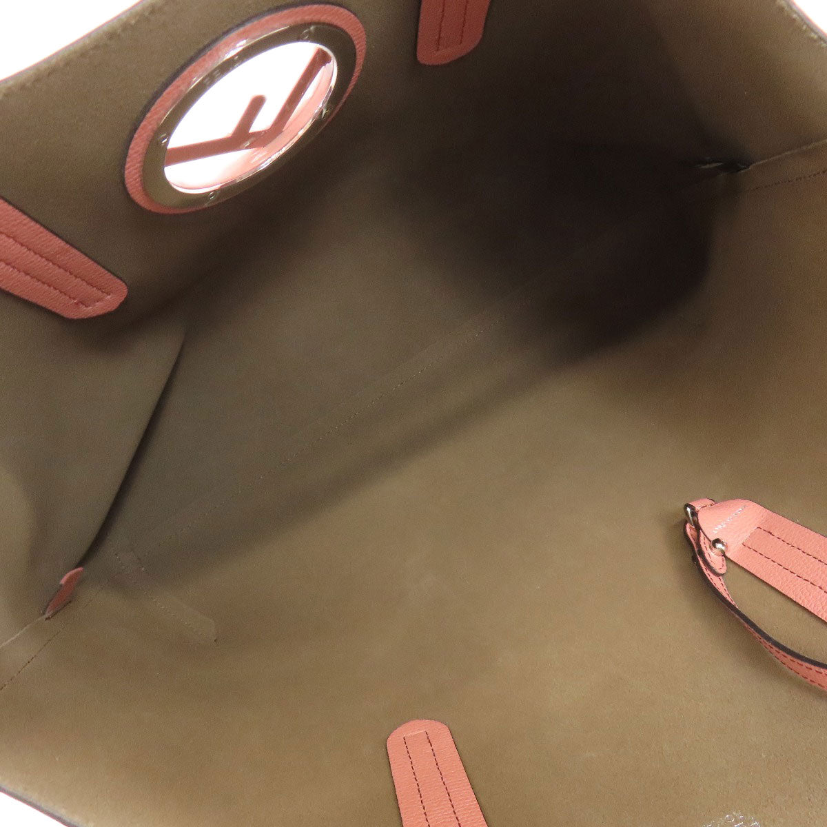 Close-up of a brown leather bag with pink accents and a circular design.