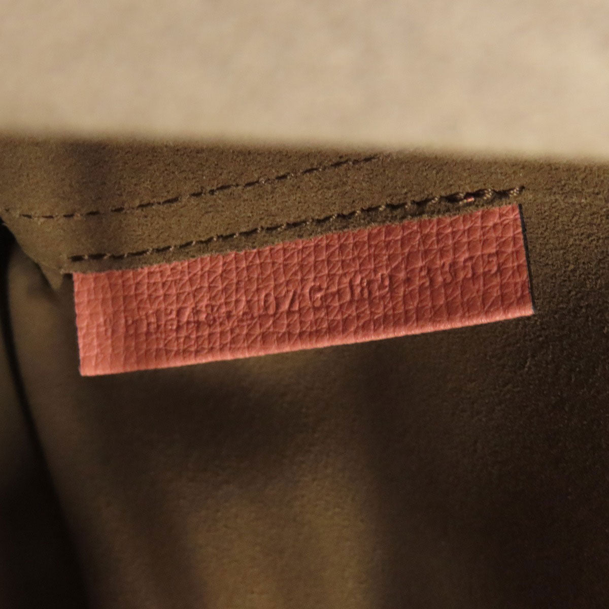 Close-up of a brown fabric with a pink label on a beige background