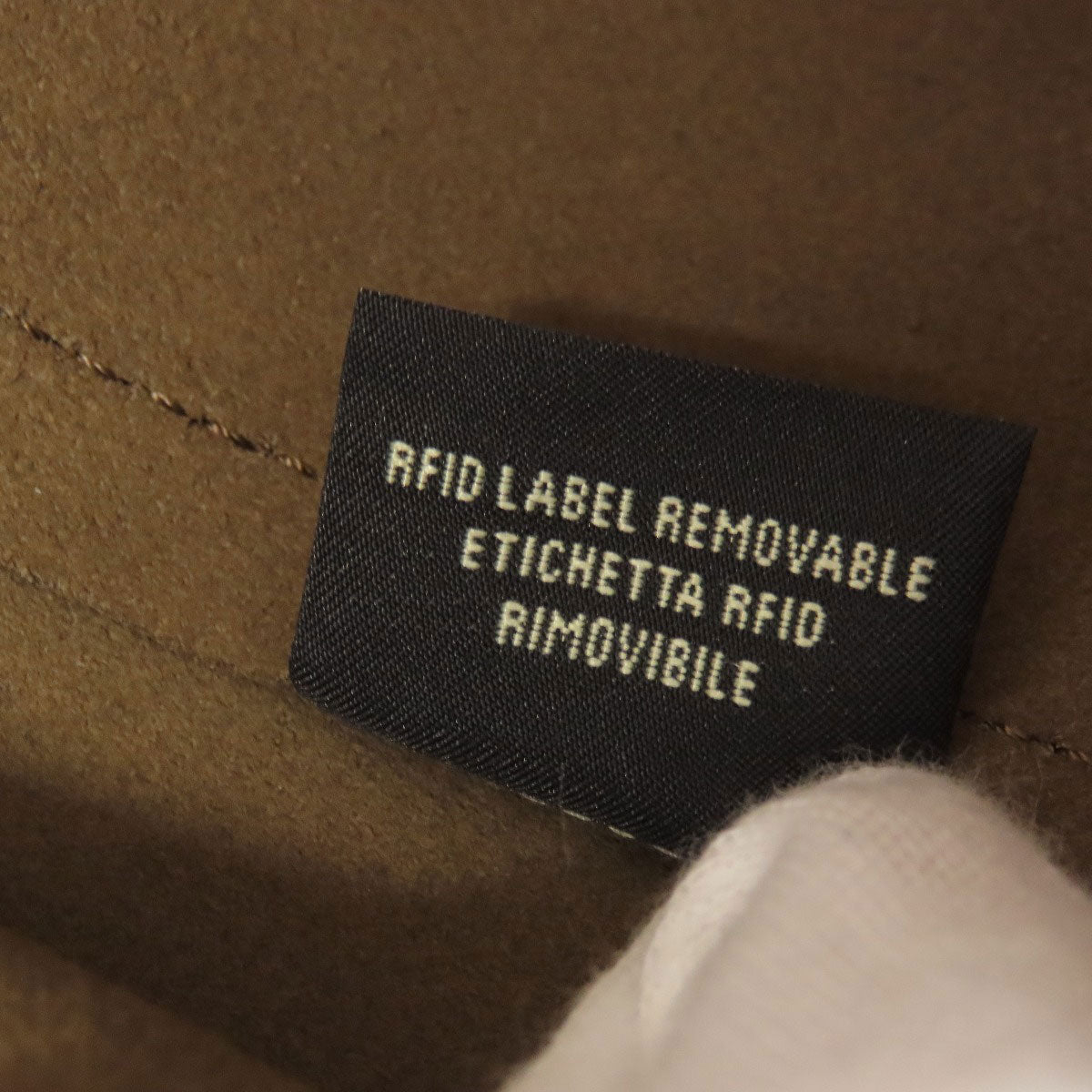RFID label on a brown fabric surface with text in multiple languages.