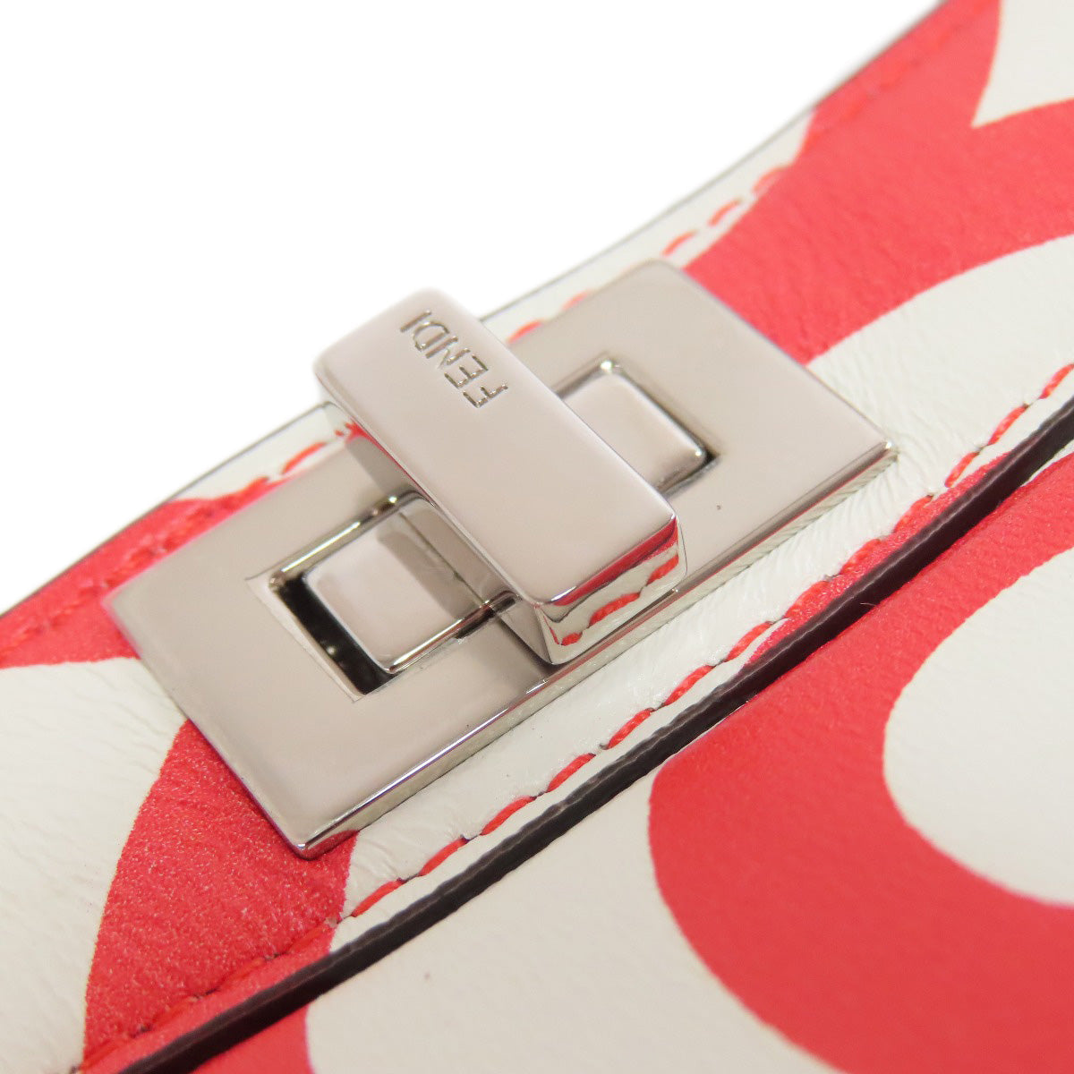 Close-up of a silver buckle on a red and white patterned bag