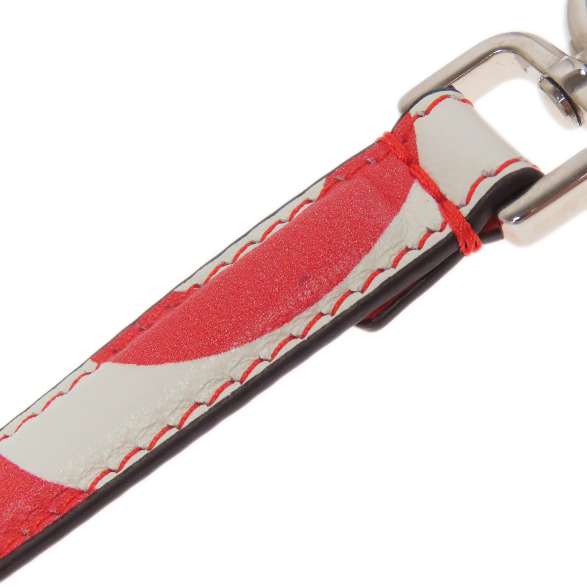 Close-up of a red and white leather strap with metal hardware on a white background