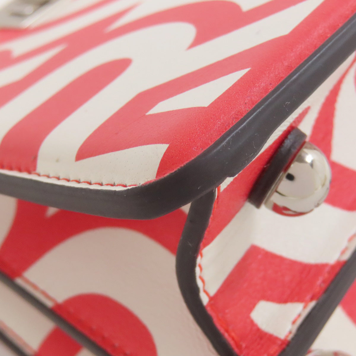 Close-up of a red and white patterned bag with a black handle.