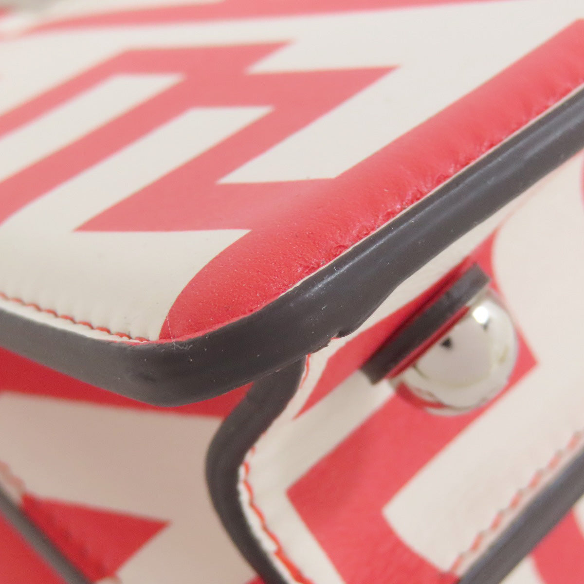 Close-up of a red and white zigzag patterned suitcase handle.