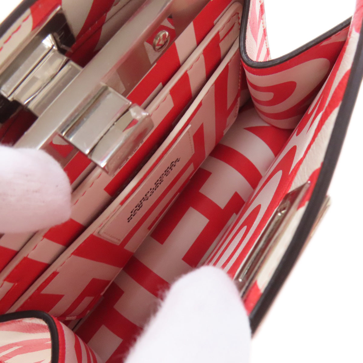 Close-up of a red and white patterned handbag with visible brand name.