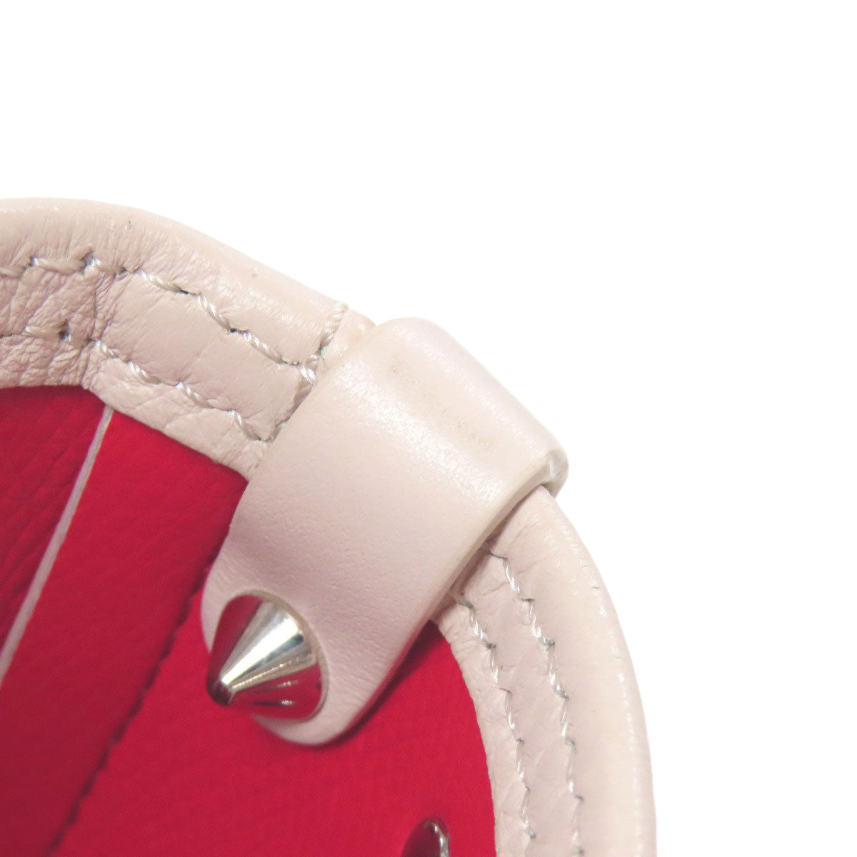Close-up of a red object with a beige strap and silver spike on a white background