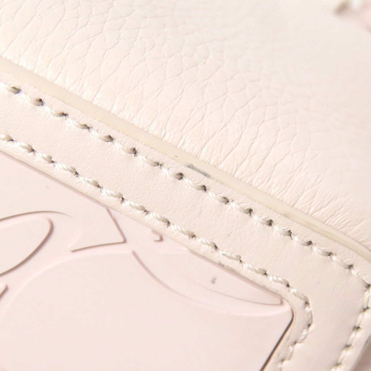Close-up of a textured surface with a brand logo and stitching details.