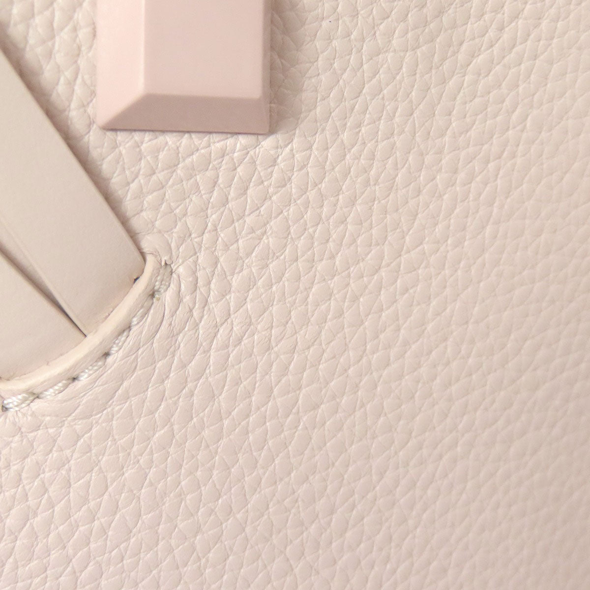 Close-up of a light pink leather bag with a visible brand logo.