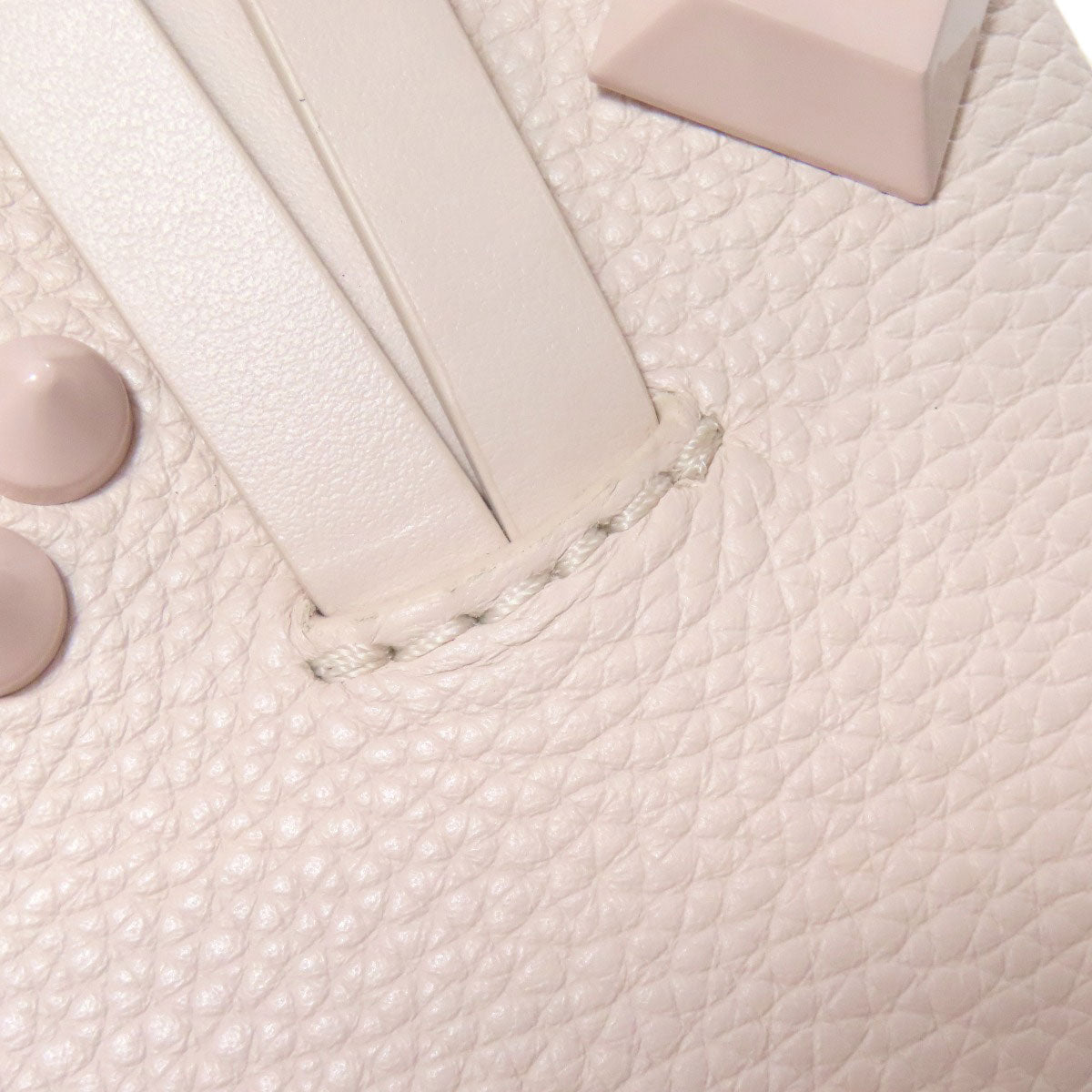 Close-up of a light pink leather bag with stitching details