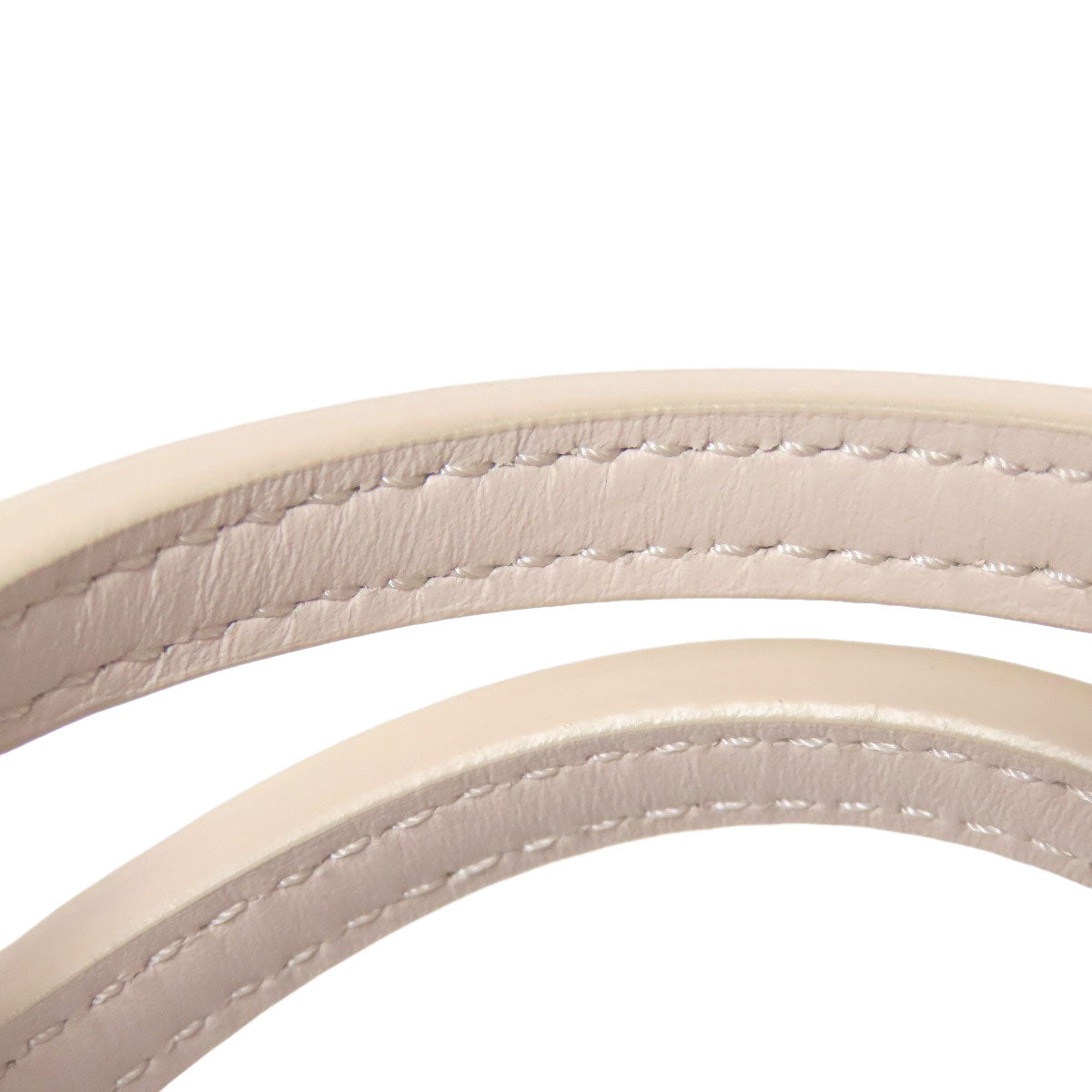 Close-up of beige leather straps with stitching on a white background