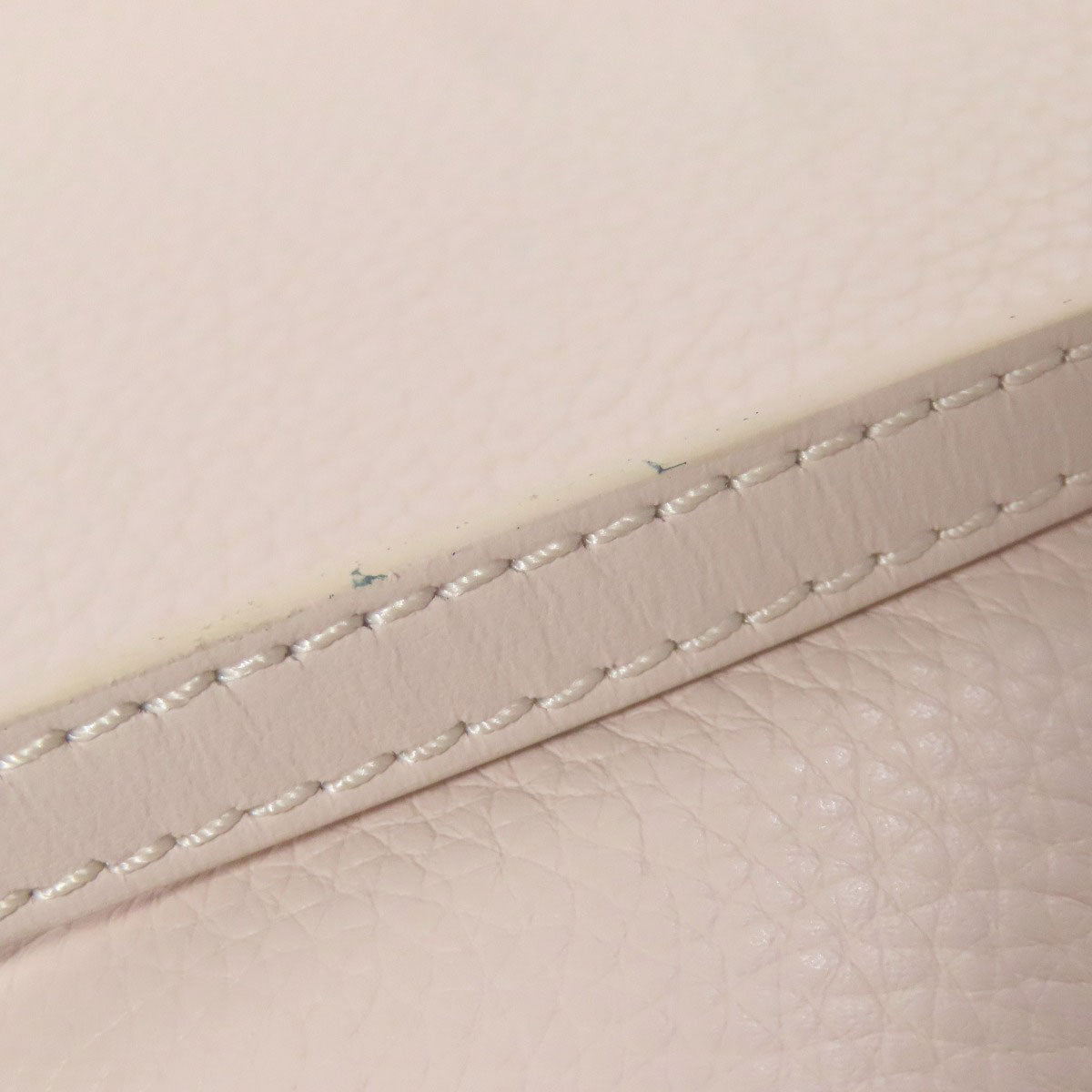 Close-up of beige leather with visible stitching on a light background