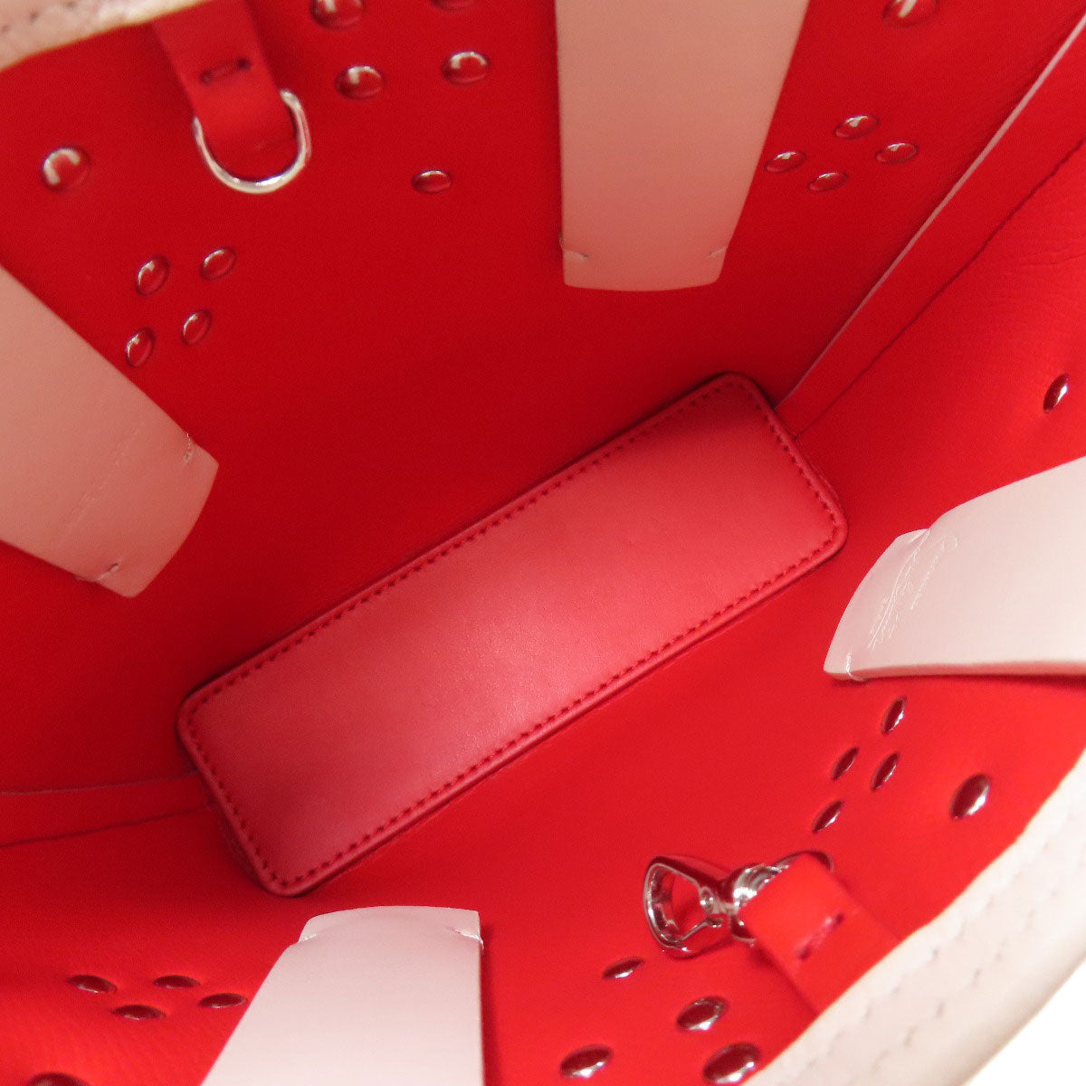 Close-up of a red leather shoe with a white sole and decorative elements.