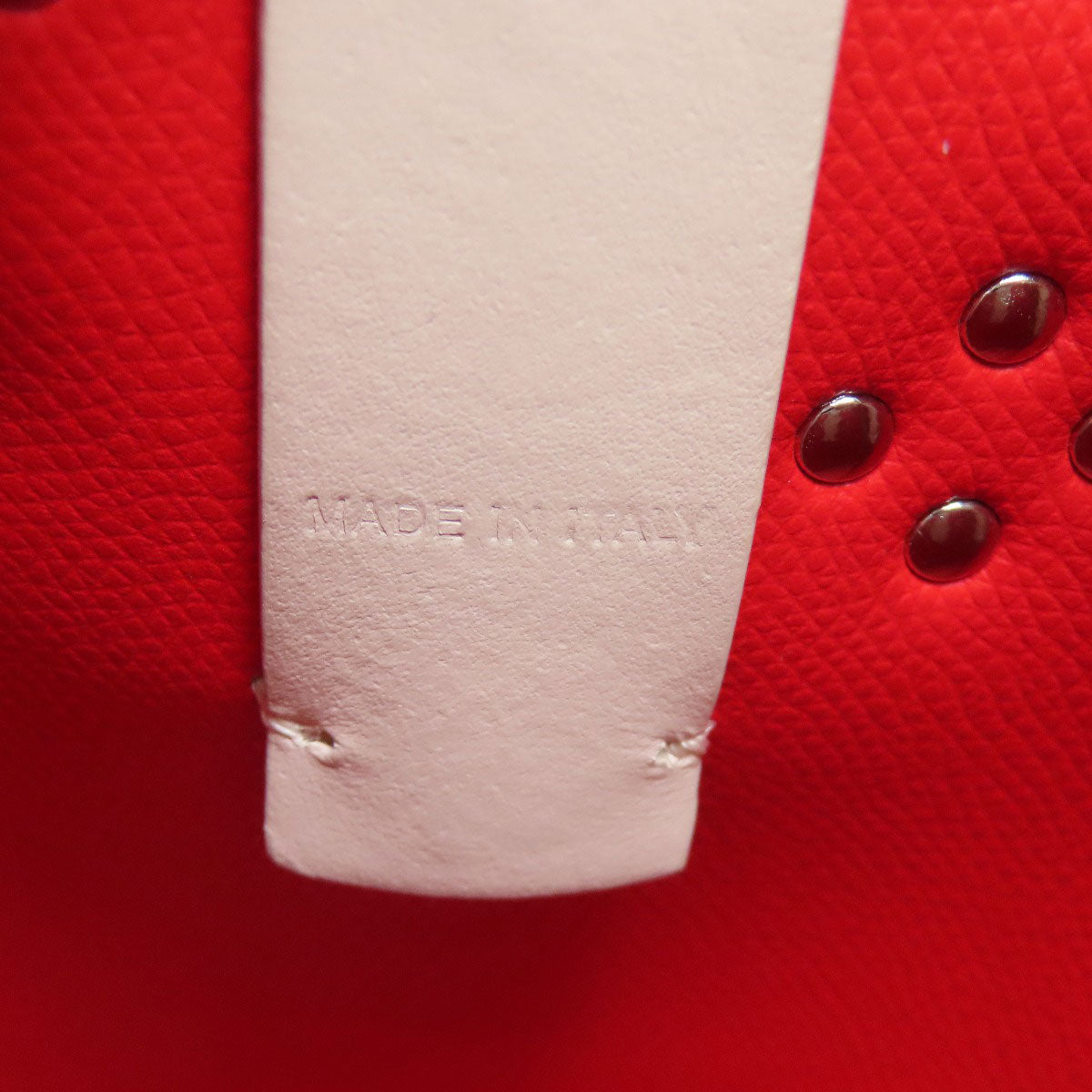 Close-up of a red leather product with 'MADE IN ITALY' stamp