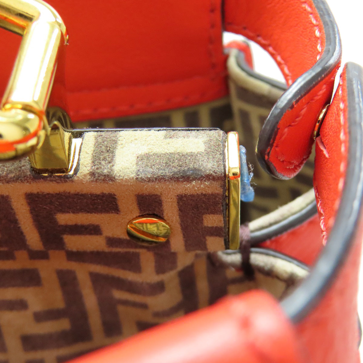 Close-up of a red handbag with gold hardware and a patterned flap.