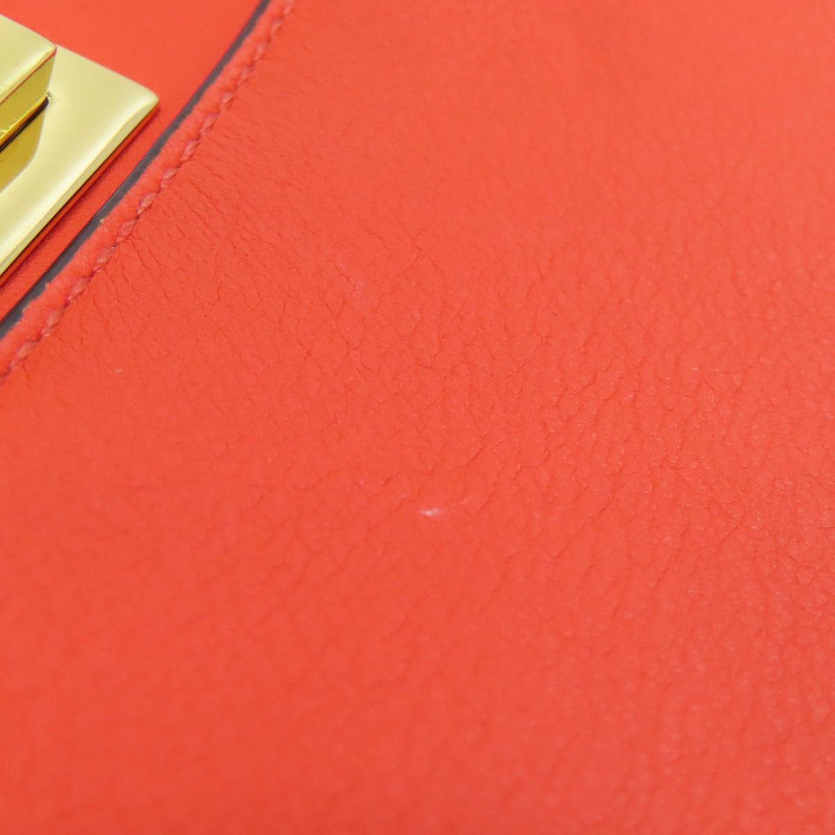 Close-up of a red leather surface with a gold buckle.
