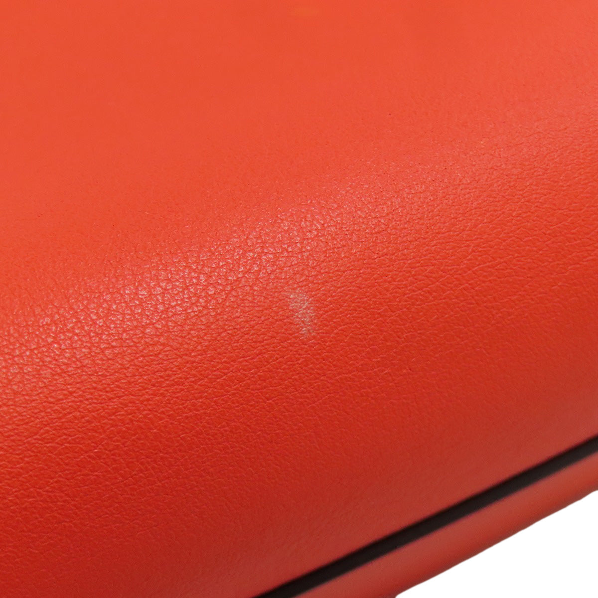 Close-up of a red leather surface with a small scratch.