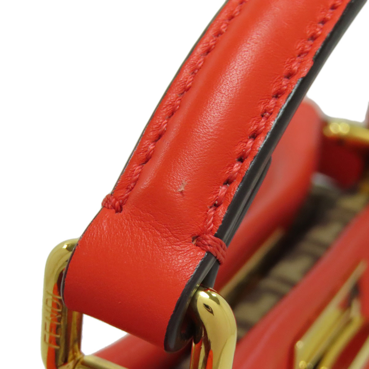 Close-up of a red leather handbag with gold hardware on a white background