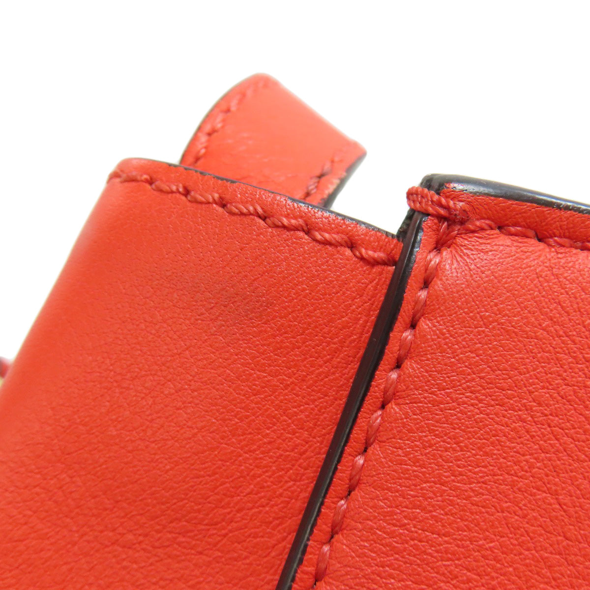 Close-up of red leather product with stitching detail on a white background