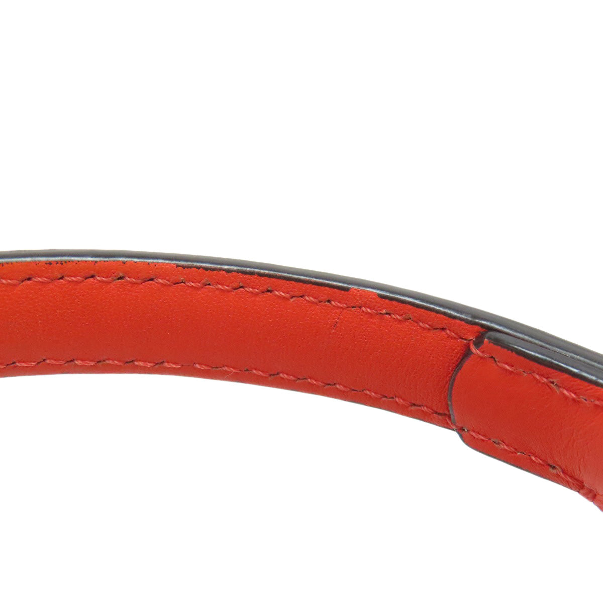 Close-up of a red leather belt with visible stitching on a white background