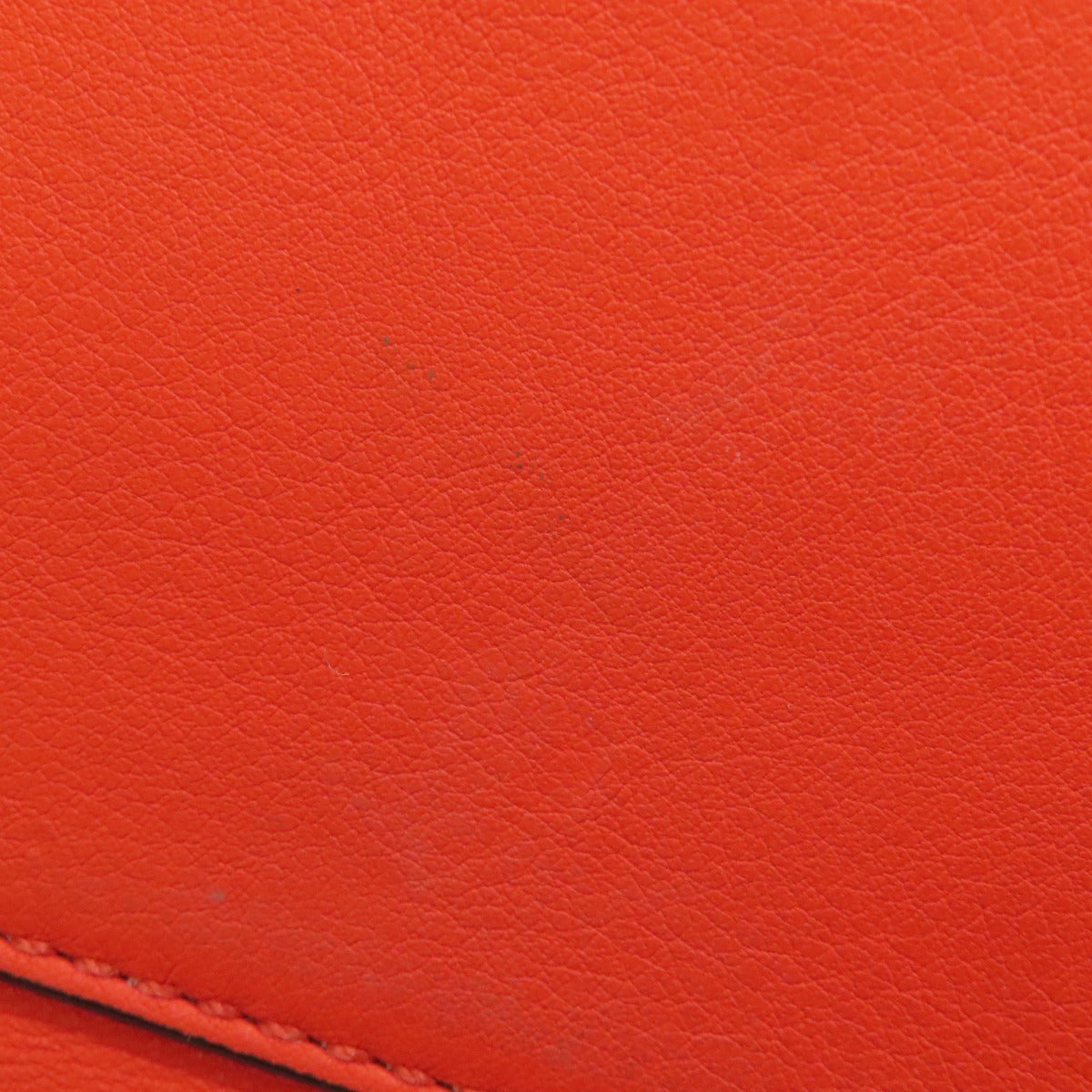 Close-up of a red leather surface with visible texture and stitching.