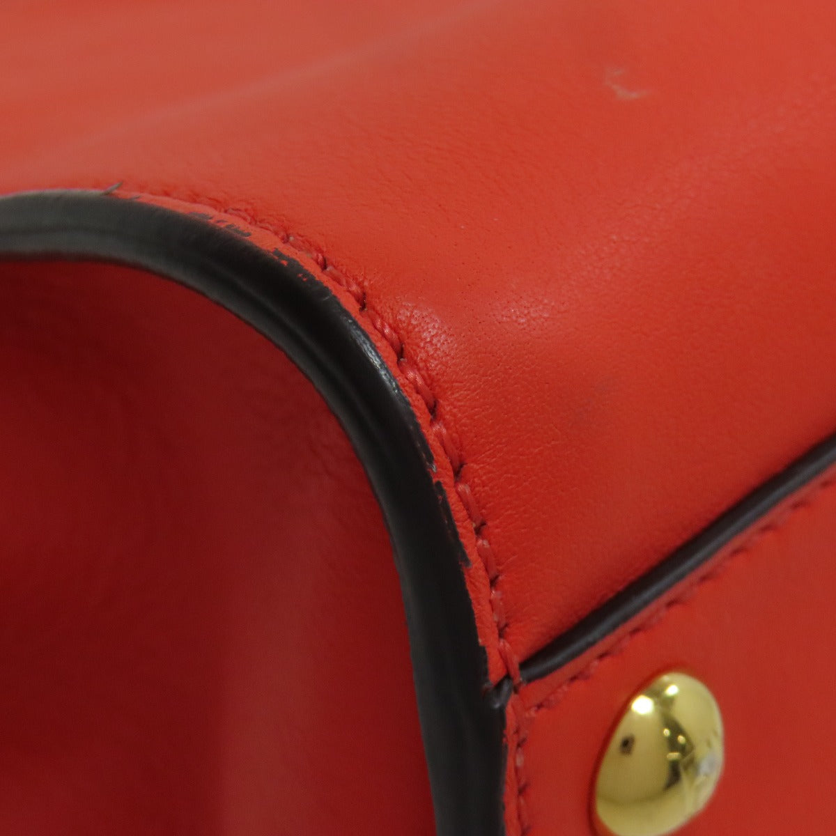 Close-up of a red leather product with a gold button