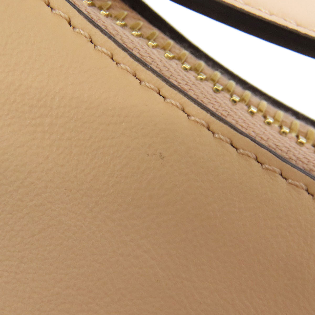 Close-up of a beige leather product with gold stitching