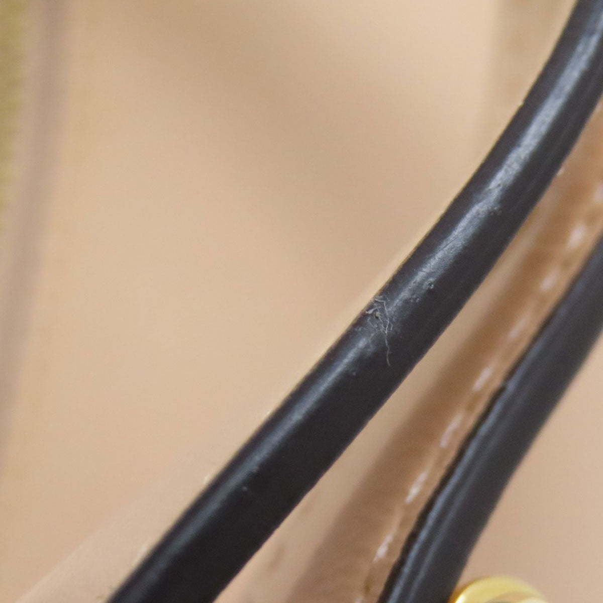 Close-up of a black leather strap with visible stitching on a beige background