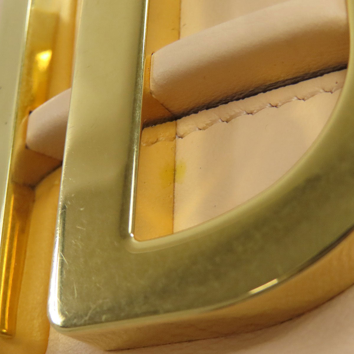 Close-up of a gold belt buckle on beige leather.