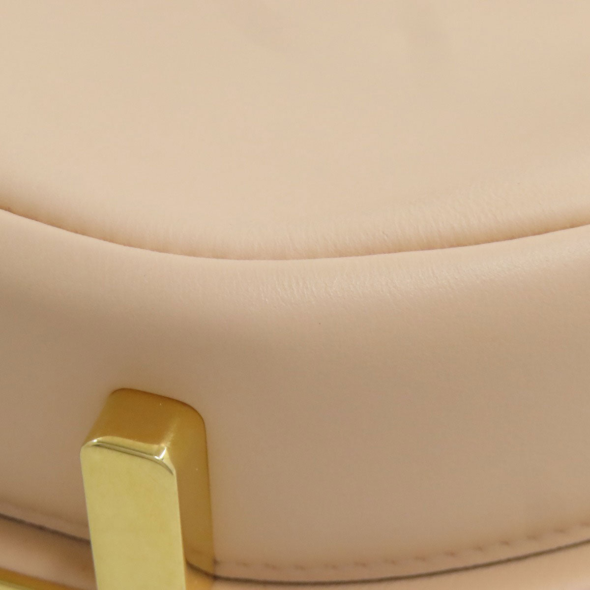 Close-up of a beige chair with a gold armrest