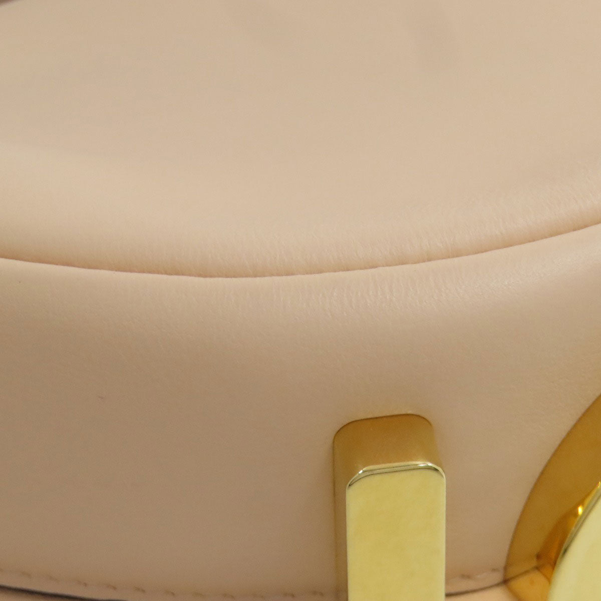 Close-up of a beige handbag with a gold clasp
