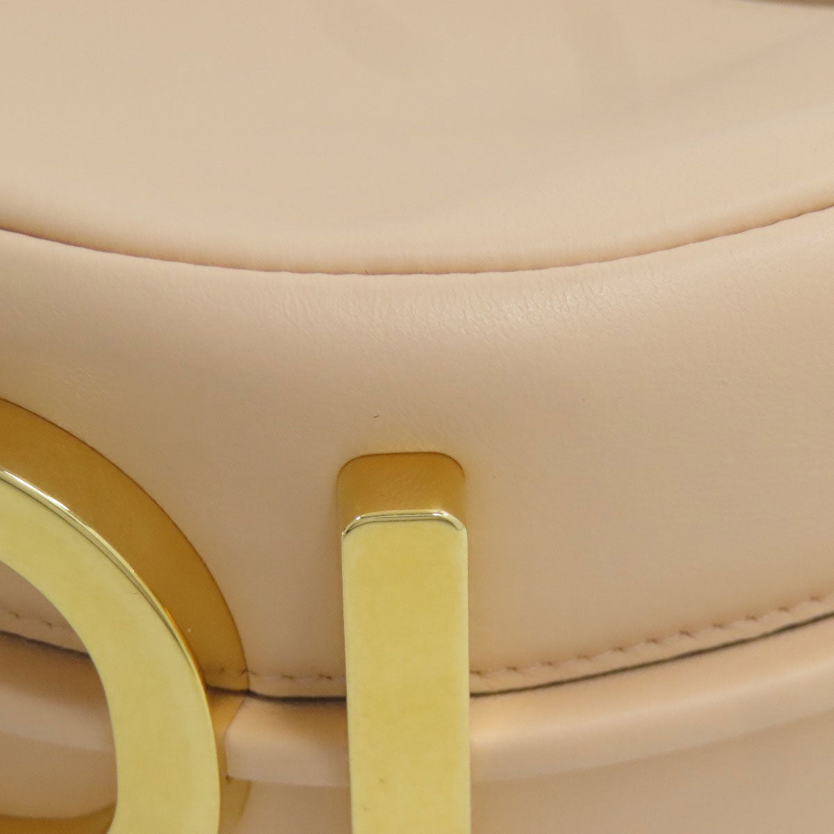 Close-up of a beige chair with gold armrests and legs.