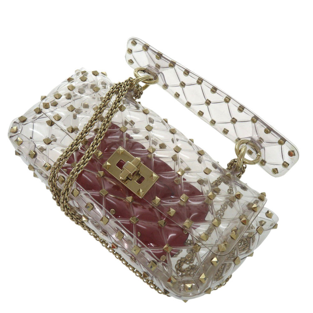 Clear handbag with gold accents and a red interior on a white background