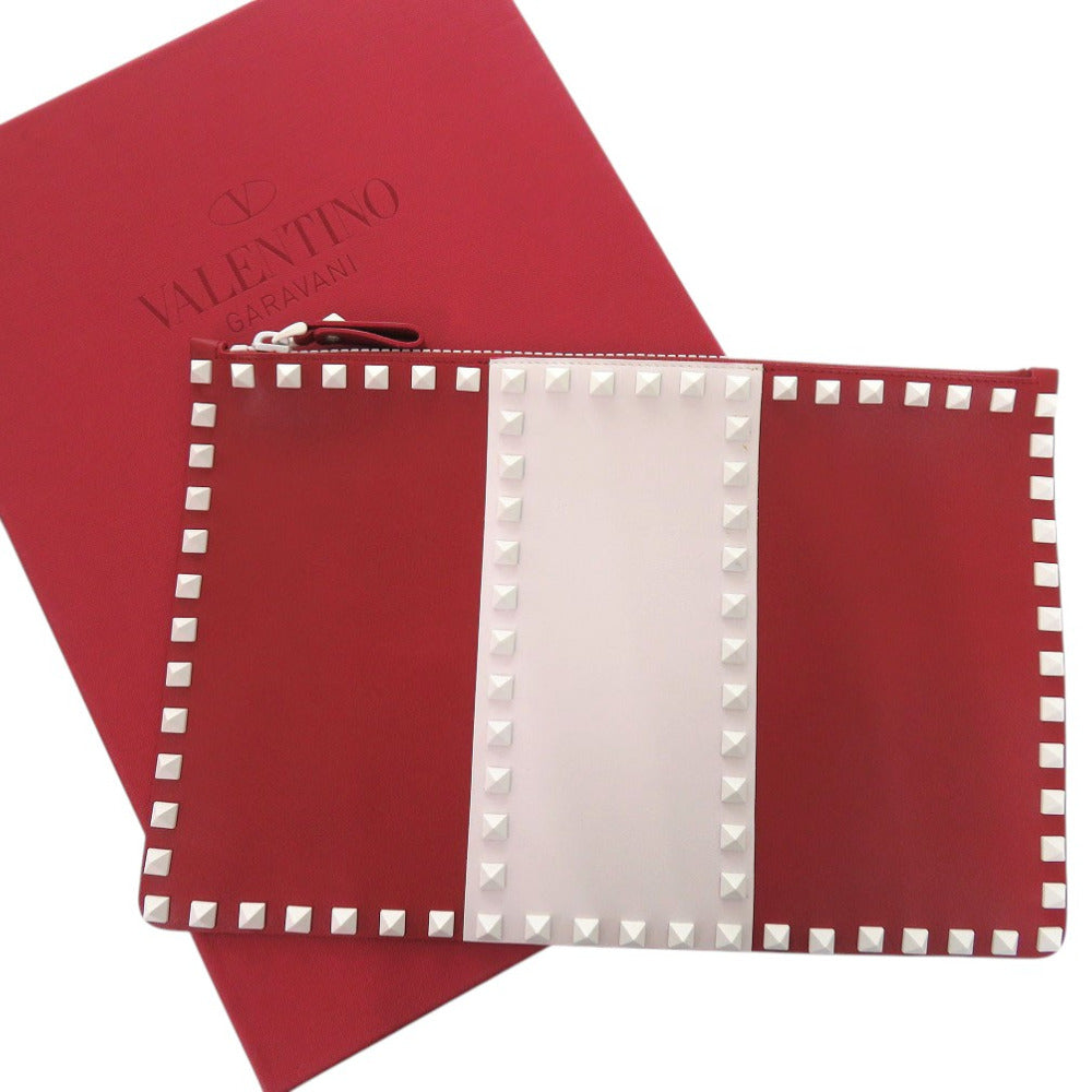 Red pouch with white stud details on a red background, featuring the brand 'Valentino'.