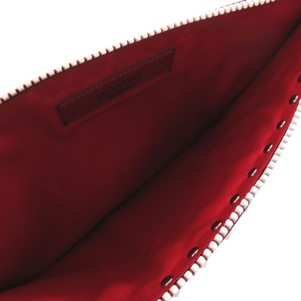 Close-up of a red clutch bag with studded details on a white background
