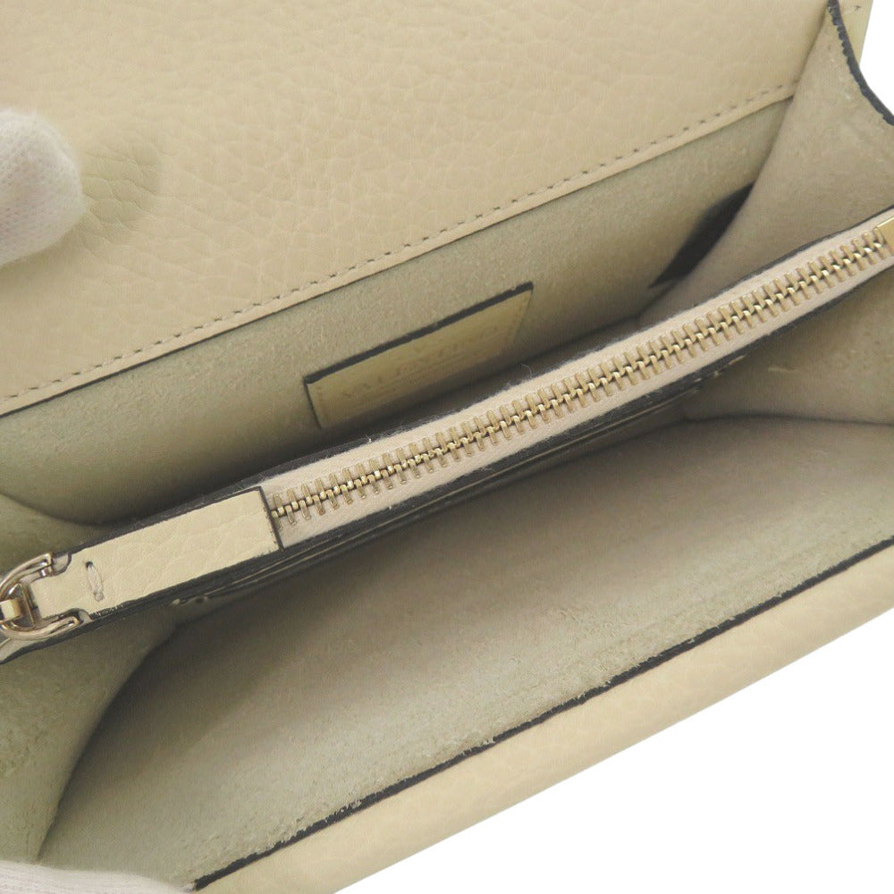 Close-up of a beige handbag with a gold zipper on a white background