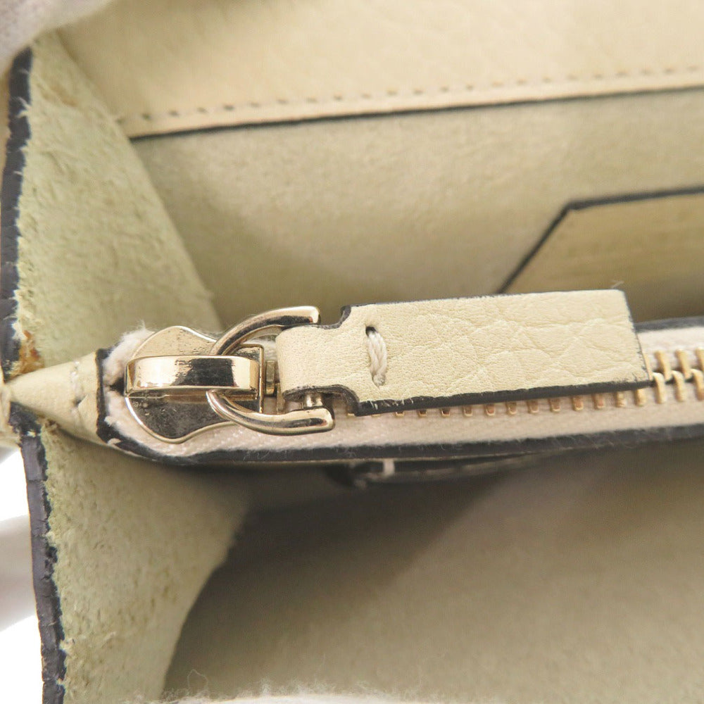 Close-up of a beige leather handbag with a gold zipper and clasp.