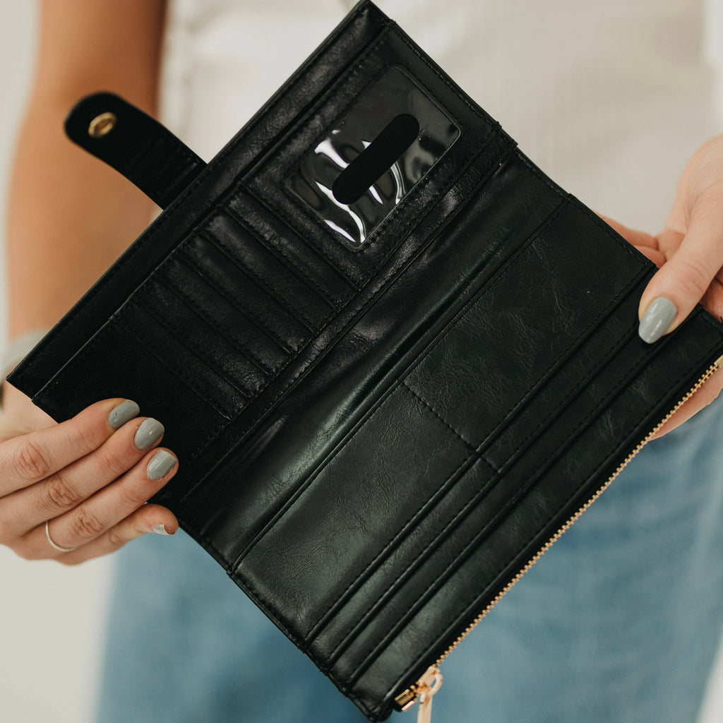 Black leather wallet held open by hands with a blurred background