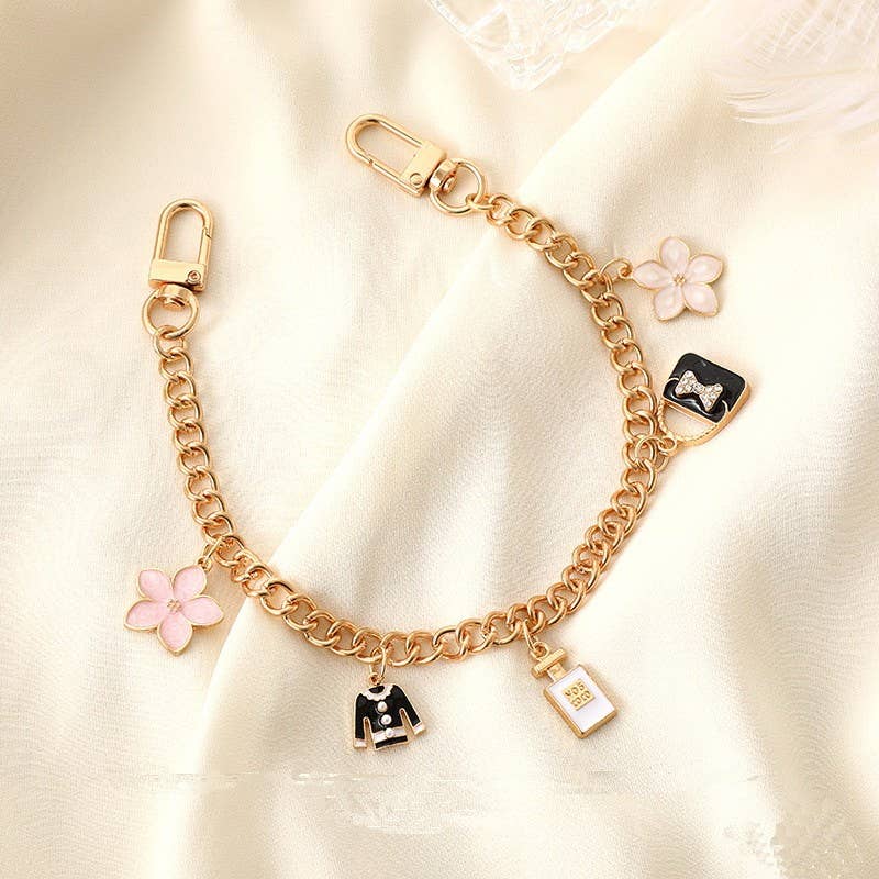 Gold chain bracelet with various charms on a light background