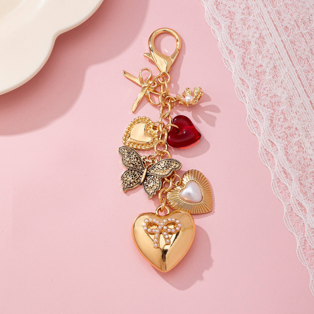 Gold charm with heart and butterfly designs on a pink background