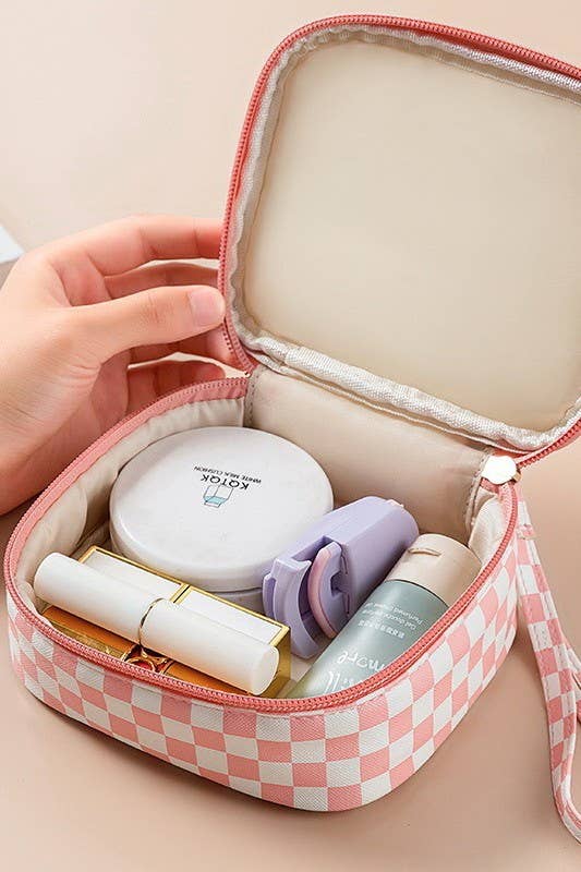Small pink and white checkered travel case with cosmetic products on a beige background
