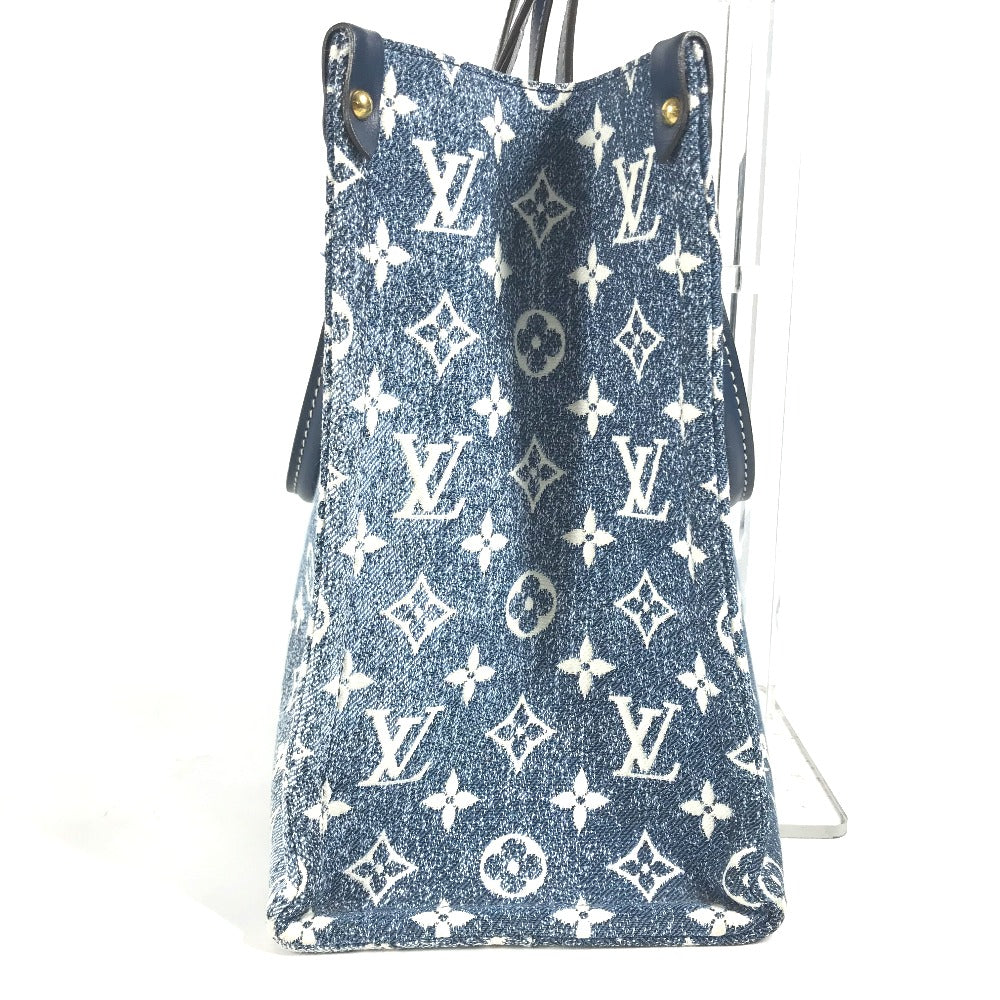 Blue denim handbag with white monogram pattern on a white background