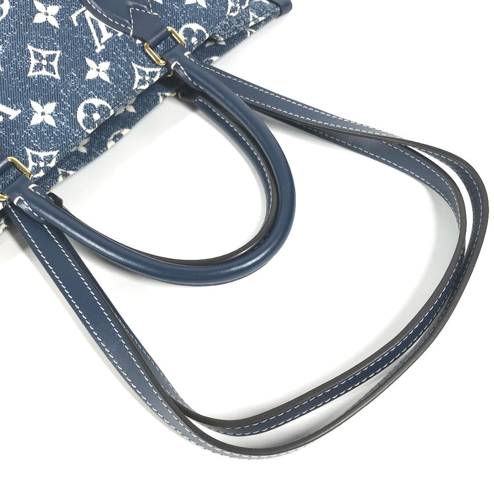 Close-up of a blue handbag with white monogram pattern on a white background
