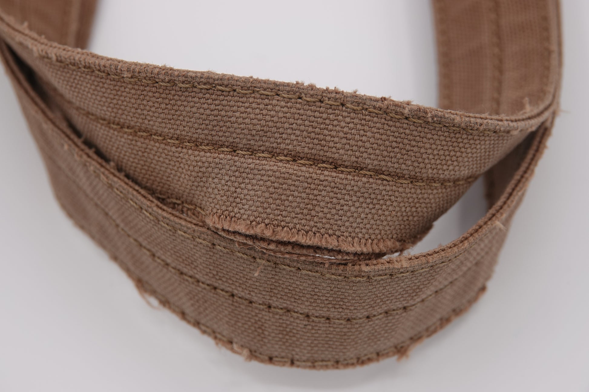 Close-up of a brown fabric belt on a white background