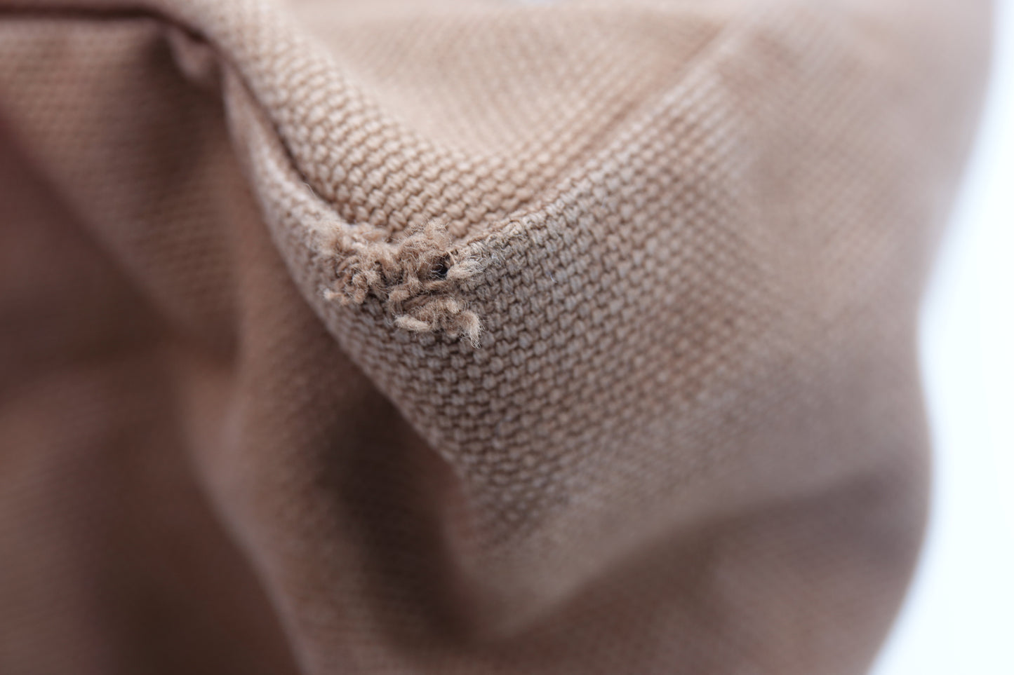 Close-up of brown fabric with visible wear and tear.