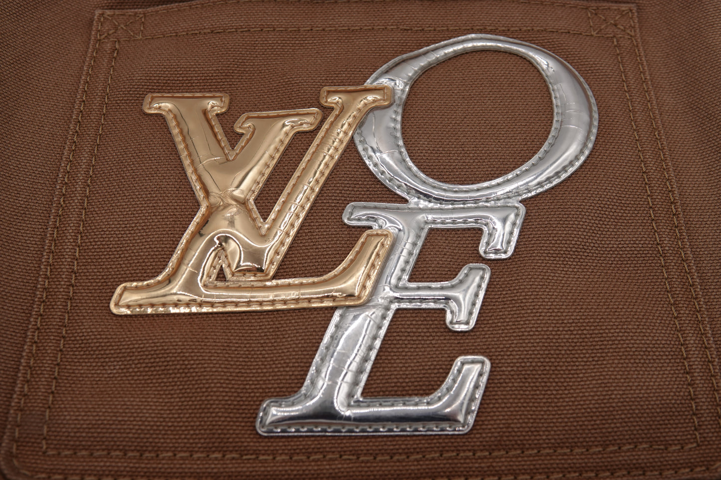 Close-up of a patch with 'LOE' letters on a brown fabric background