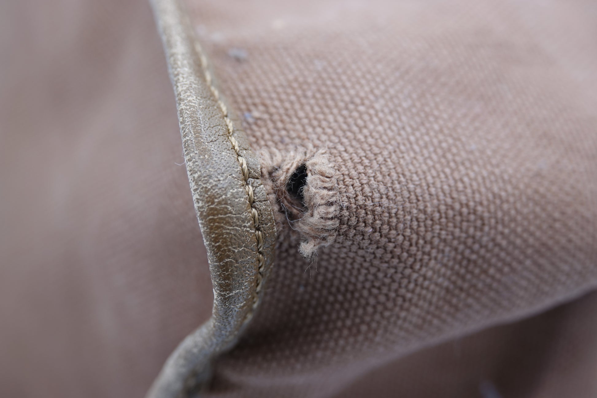 Close-up of a fabric edge with a small tear on a brown background